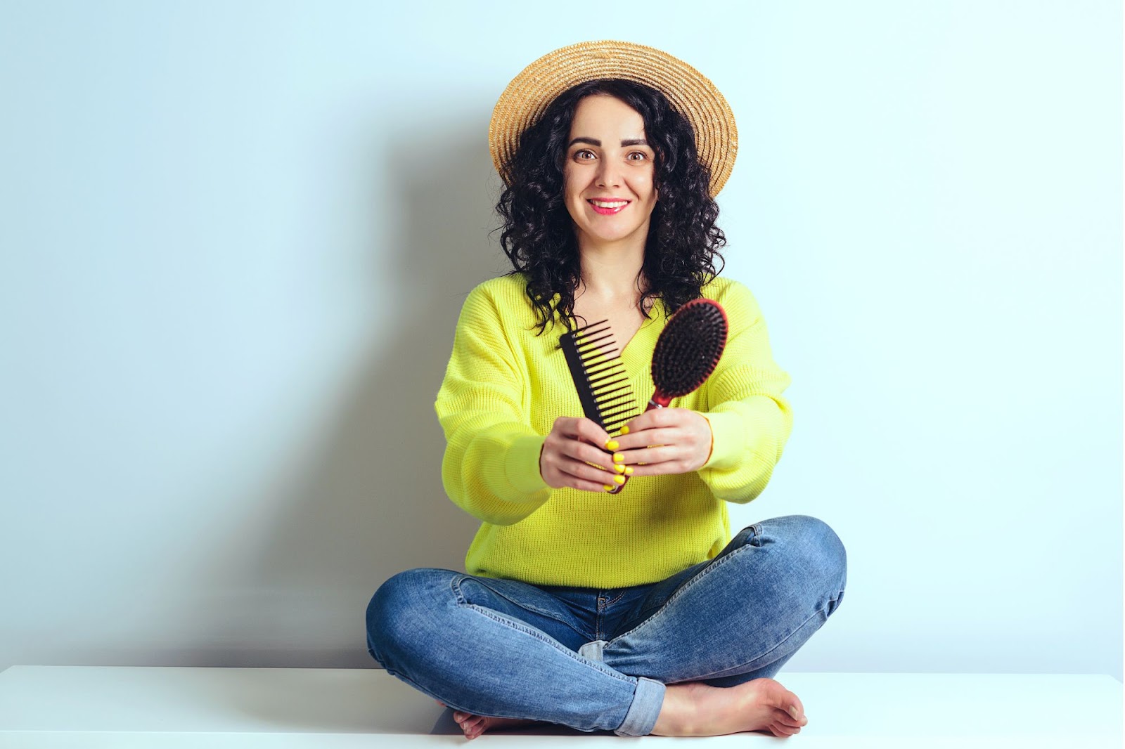 woman with curly hair holding comb and brush