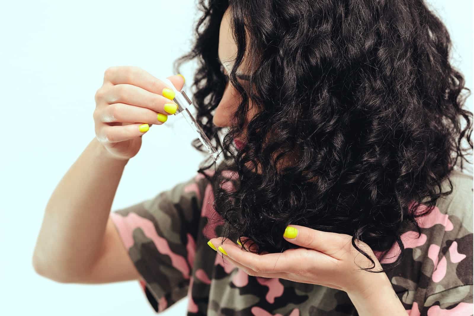 woman adding oil to curly hair